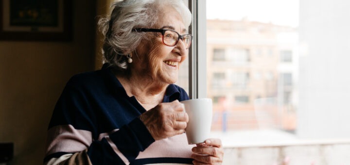 zufriedene ältere Dame schaut aus dem Fenster
